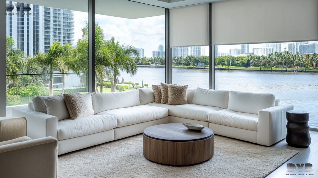 A Family Room in West Palm Beach, FL, styled in a Contemporary design with a view of Canals. The room features a plush white sectional sofa and a sleek coffee table from Ethan Allen. The windows are large and feature Roller Shades, partially closed, allowing for soft light to filter through. Shot type: natural light focus
